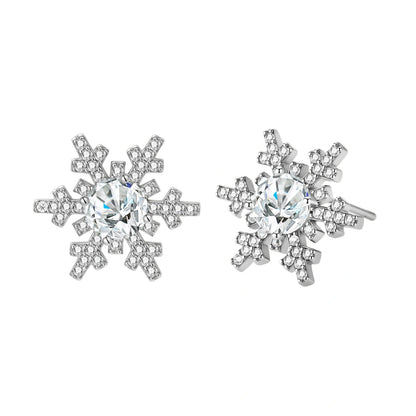 Sterling silver snowflake stud earrings with brilliant moissanite centers and intricate geometric patterns on cream background