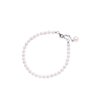 Adjustable bracelet featuring lustrous freshwater pearls with rhodium-plated sterling silver clasp on cream background.