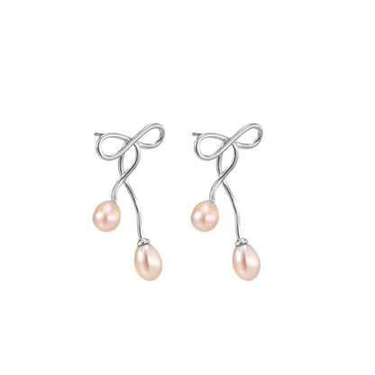 Rhodium-plated silver earrings with organic vine curves and two peachy freshwater pearls on cream background