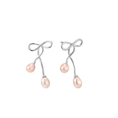 Rhodium-plated silver earrings with organic vine curves and two peachy freshwater pearls on cream background