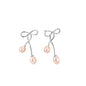 Rhodium-plated silver earrings with organic vine curves and two peachy freshwater pearls on cream background
