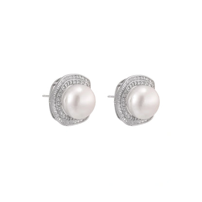 Rhodium-plated sterling silver stud earrings with round freshwater pearls surrounded by geometric crystal halos on cream background.