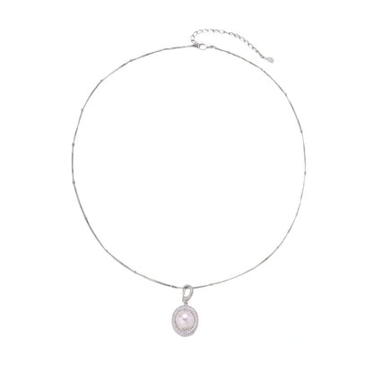 Oval sterling silver pendant with crystal halo surrounding a white freshwater pearl on delicate chain