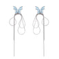 Long silver-tone earrings with powder blue enamel butterfly studs and flowing chain tassels on cream background