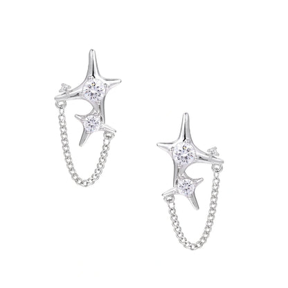 Silver star studs with crescent moon cutouts and zirconia stones connected by delicate chains on white background