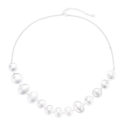 Graduated pearl-finish silver discs forming an organic bubble bib necklace on delicate chain against cream background.