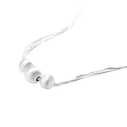Sterling silver multi-strand necklace with three brushed round beads on cream background