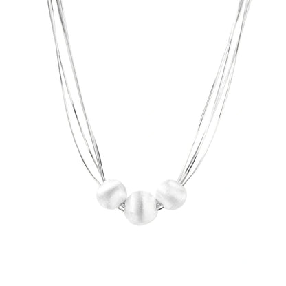 Sterling silver multi-strand necklace with three brushed round beads on cream background