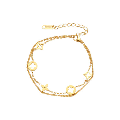 Double-layer gold-plated bracelet with quatrefoil and star charms on cream background, 18K gold finish.