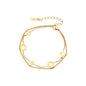 Double-layer gold-plated bracelet with quatrefoil and star charms on cream background, 18K gold finish.